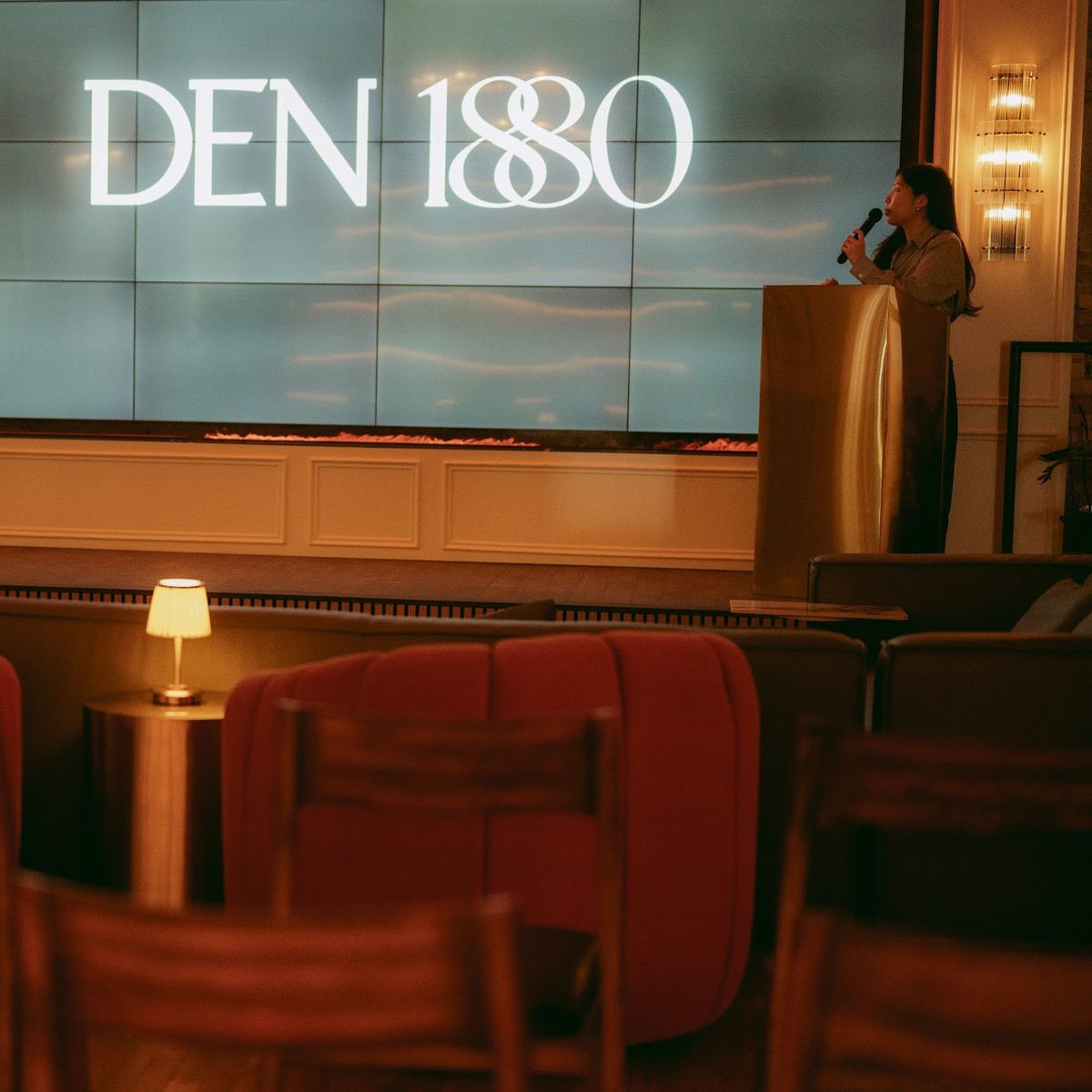A speaker addressing guests at Den 1880