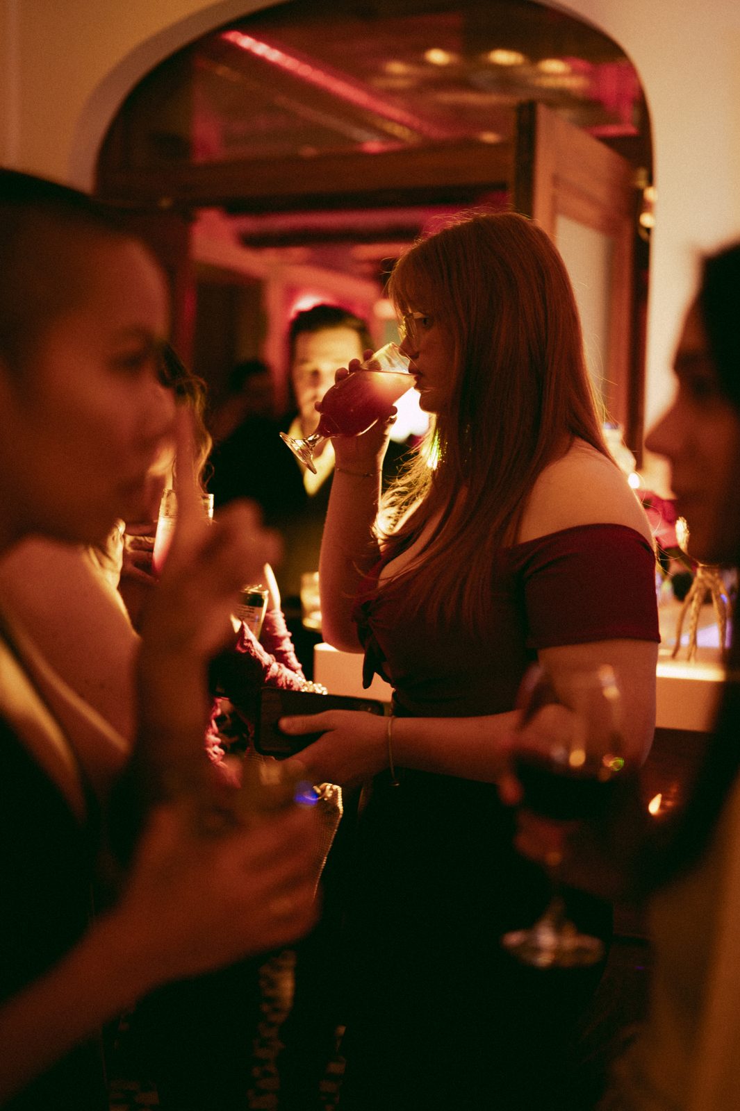 Guests with cocktails at the bar under warm lighting during an evening event at Den 1880