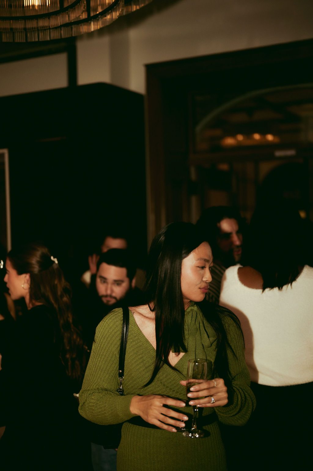 A guest with a glass of sparkling wine among the crowd at a Den 1880 holiday event
