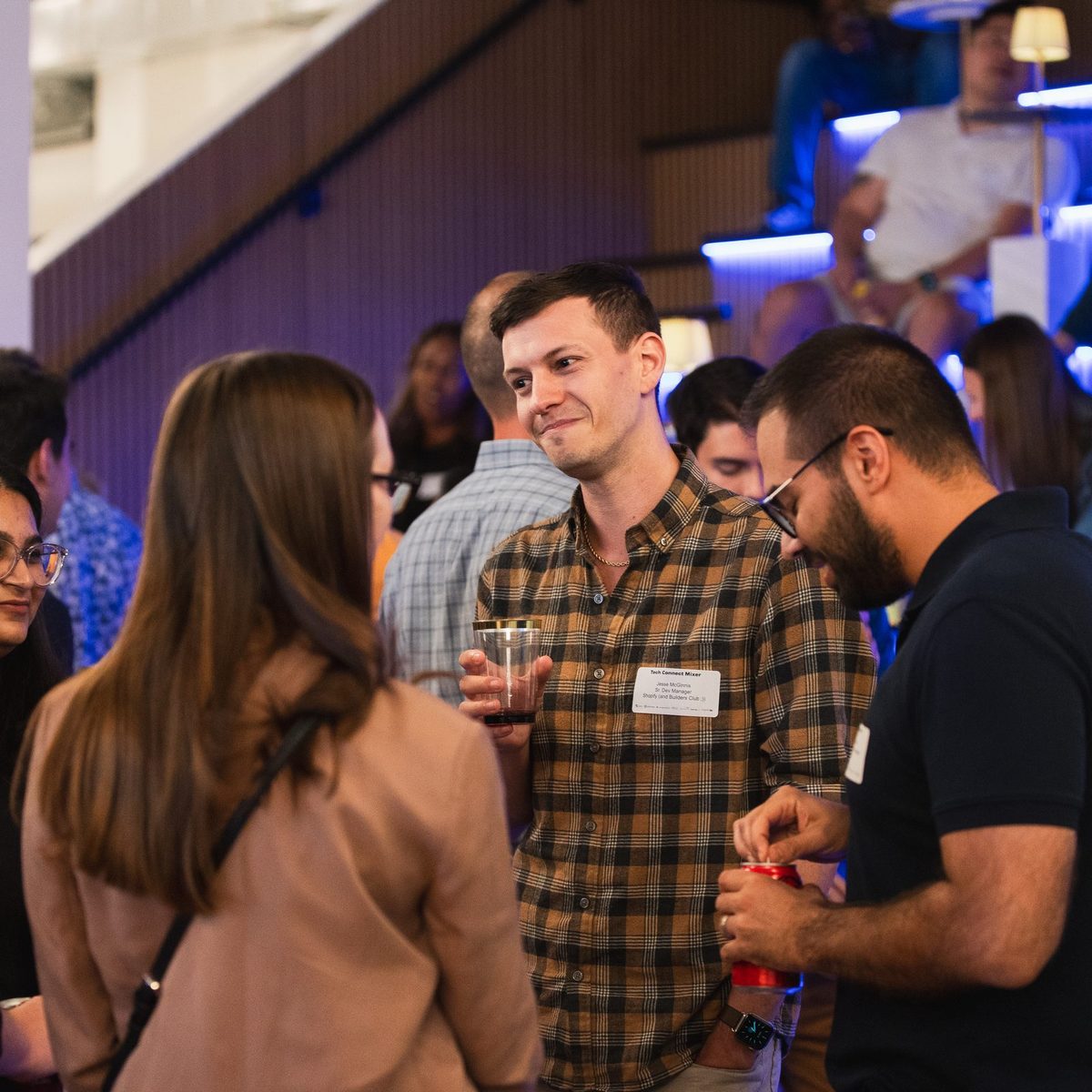 Guests in name tags talking over drinks at a reception in the Den 1880 lounge