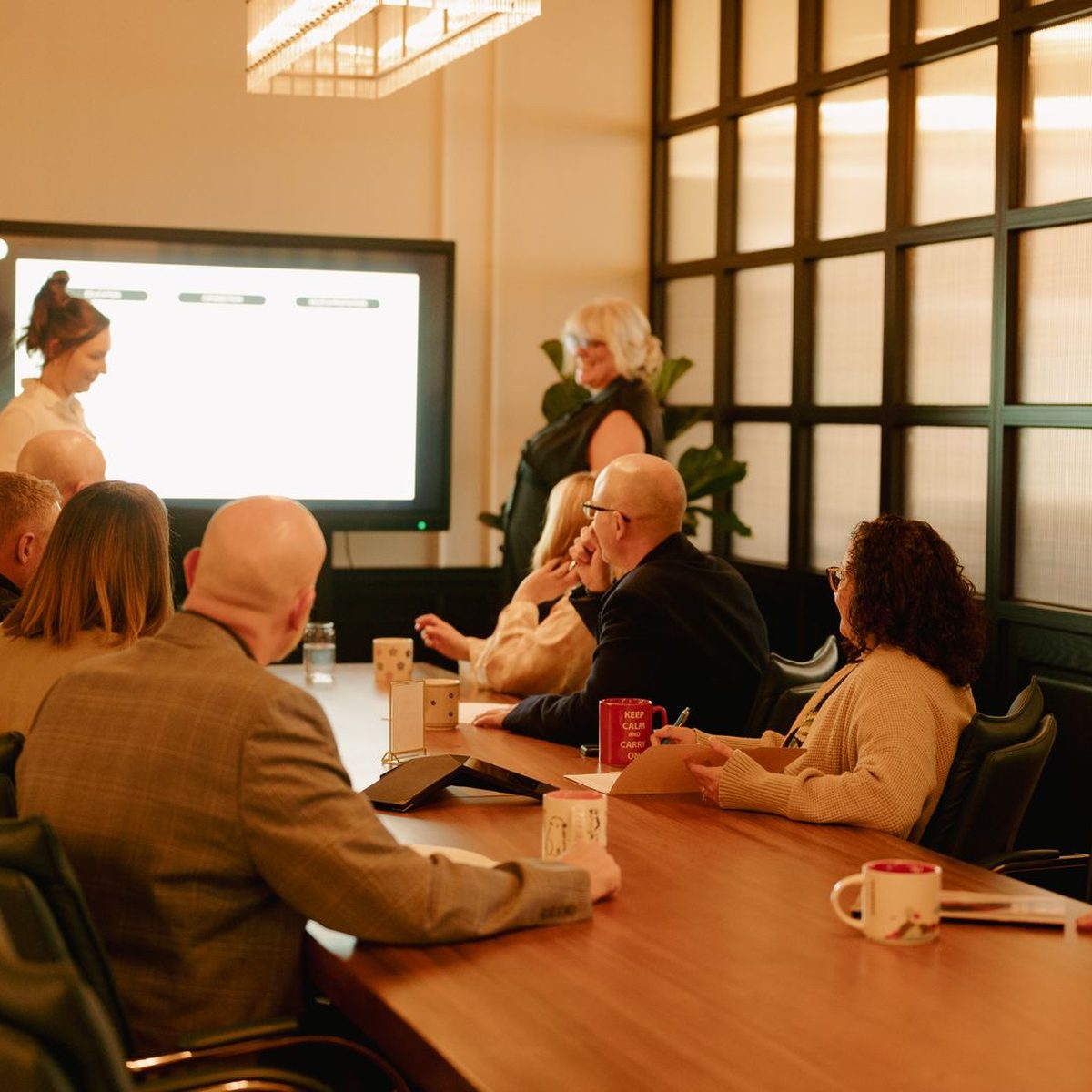 A team around the boardroom table at Den 1880 with a presentation on the screen behind them