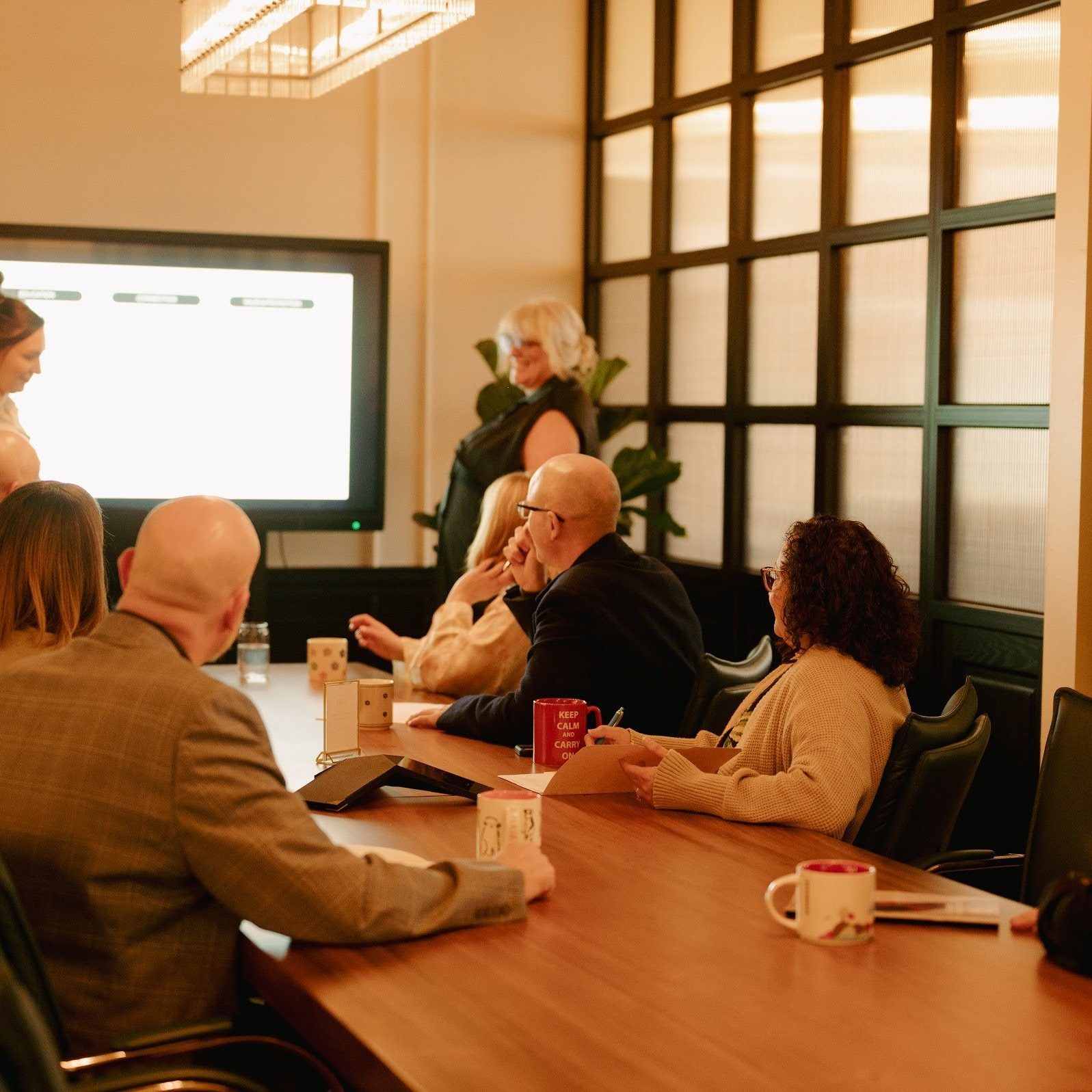 A session under way around the long table in The Grand Boardroom at Den 1880, with the presentation on the wall screen