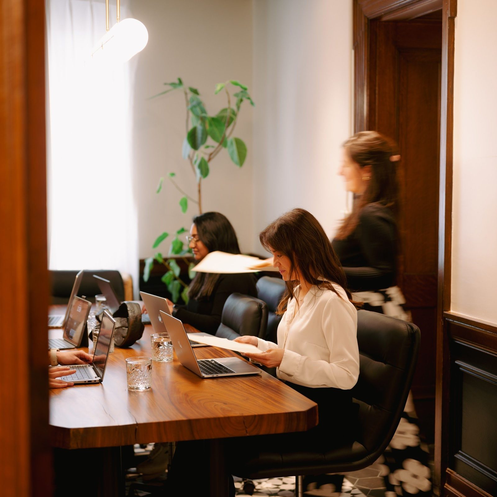 Someone working head-down at a laptop in a quiet panelled meeting room at Den 1880