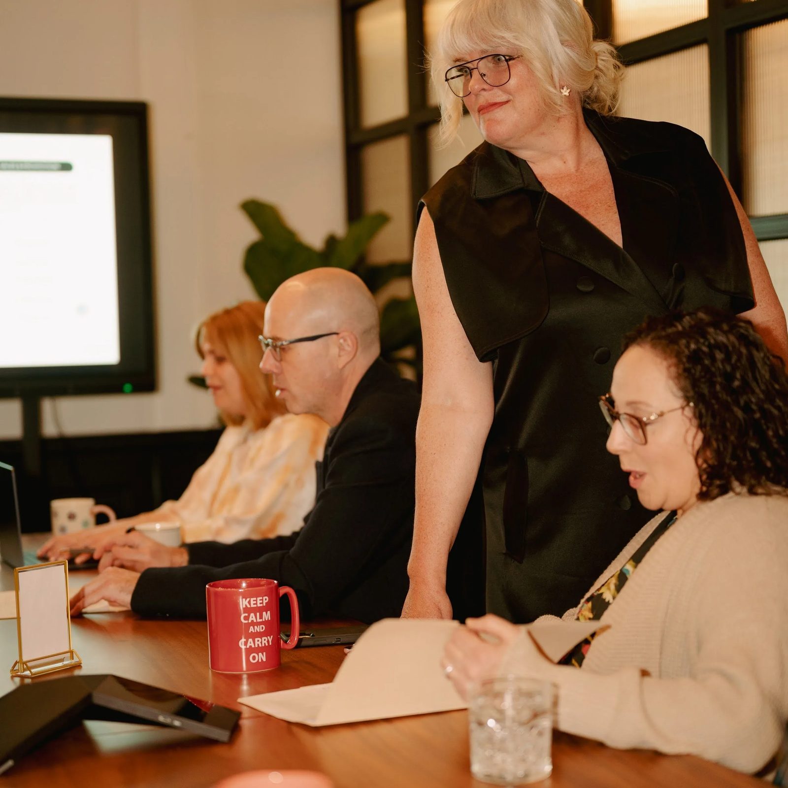 A facilitator standing at the head of the table talking with the room during a session at Den 1880