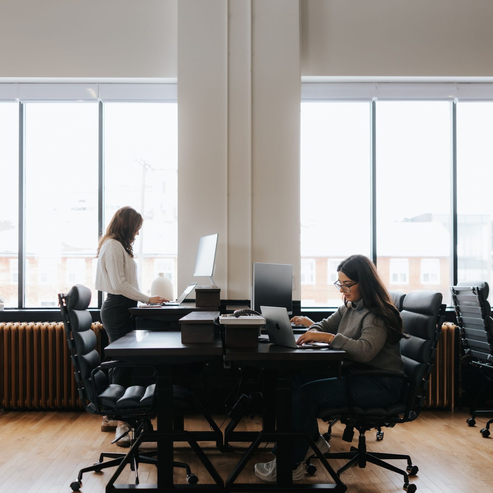 Two people working at desks in a private office on the Teams Floor at Den 1880 in Uptown Waterloo