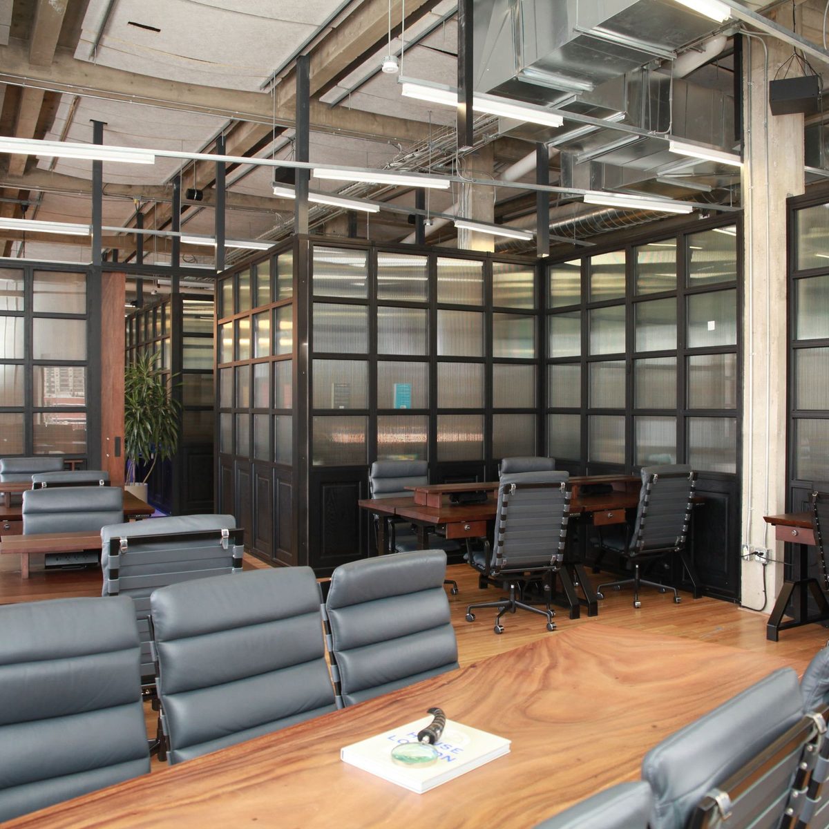 A larger team suite at Den 1880 with a long boardroom table, eight chairs and reeded-glass partitions