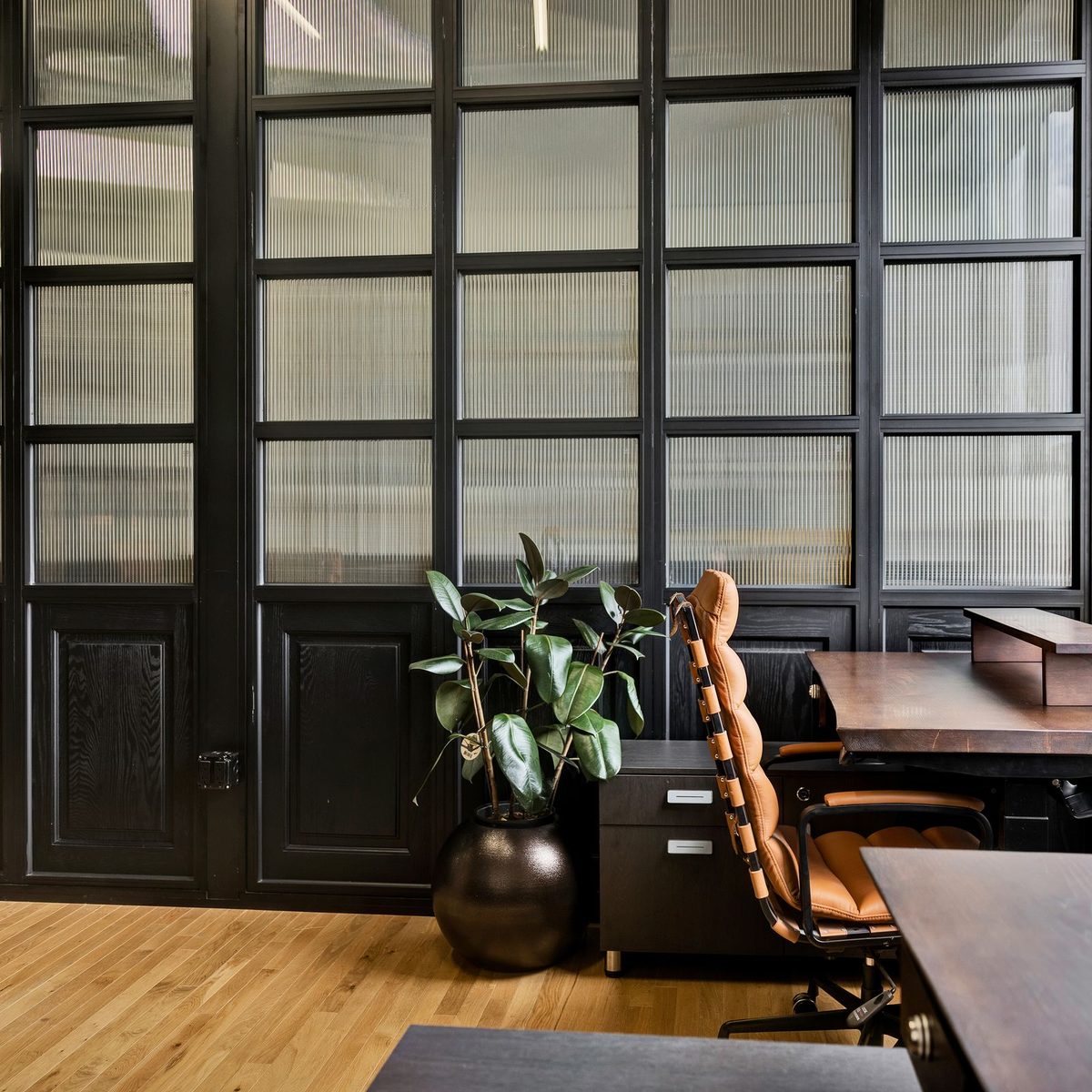 A private office at Den 1880 with a desk under the window, a potted plant and the original heritage doors