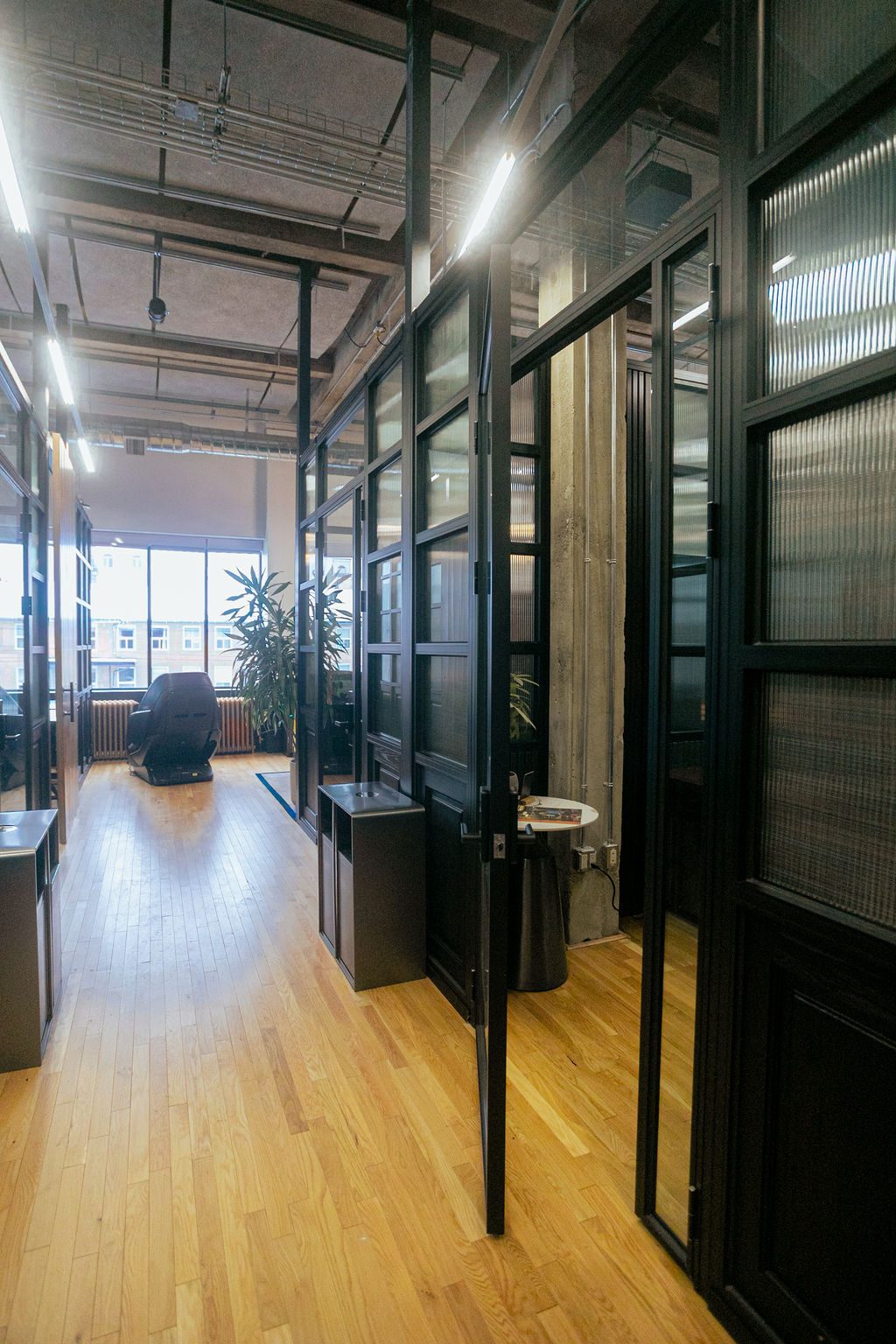 The corridor running between the glass-walled private office suites on Den 1880's Teams Floor