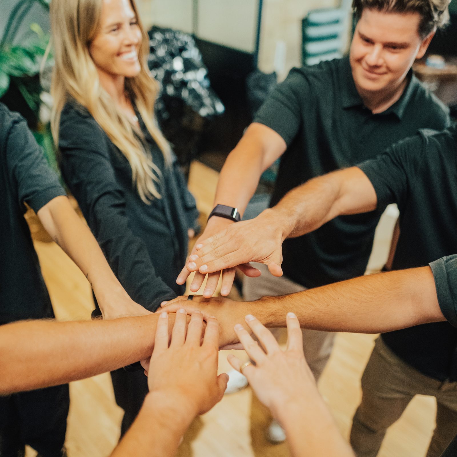 A team putting their hands together in a huddle during a team-building session at Den 1880