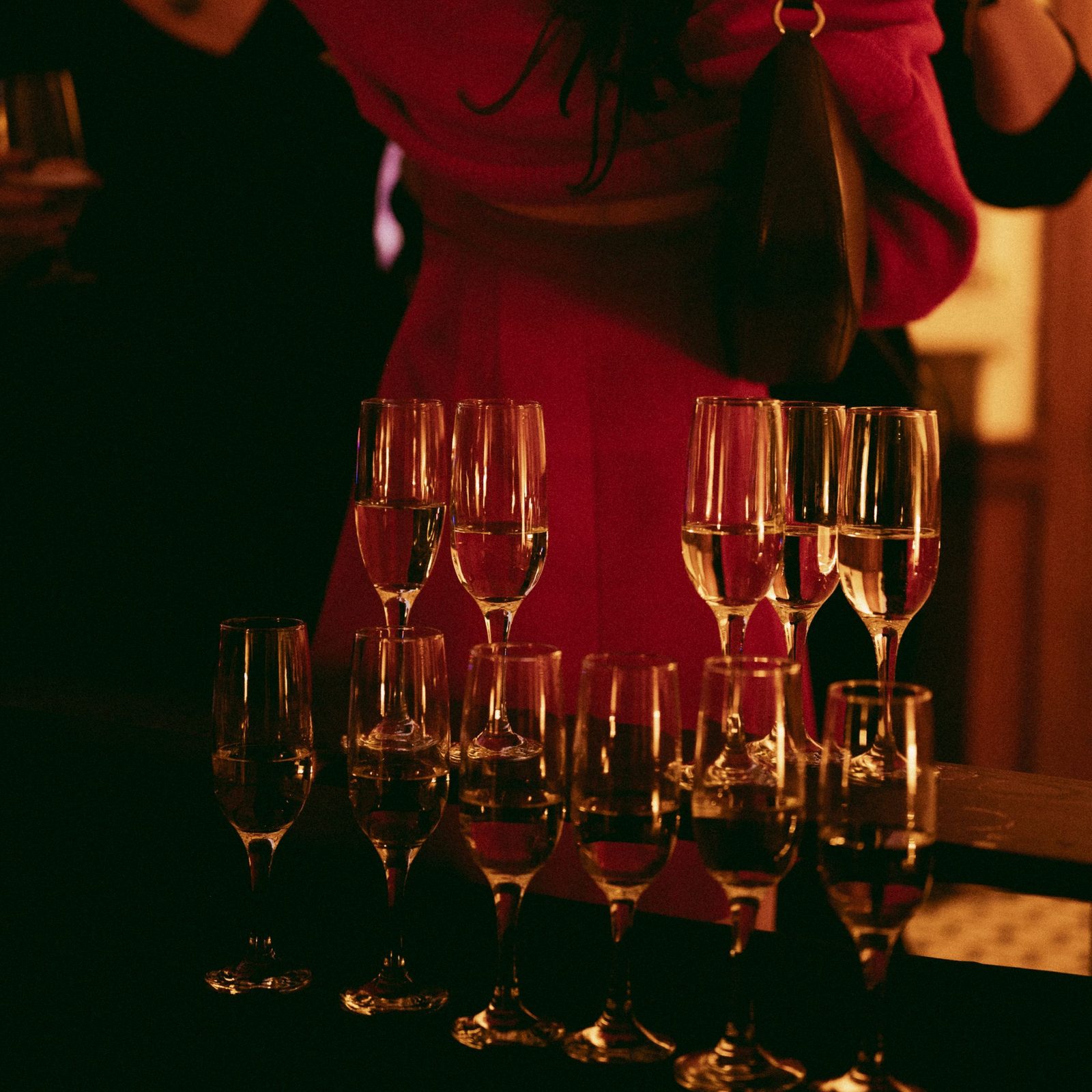 Champagne poured into a row of flutes on the bar at a celebration at Den 1880