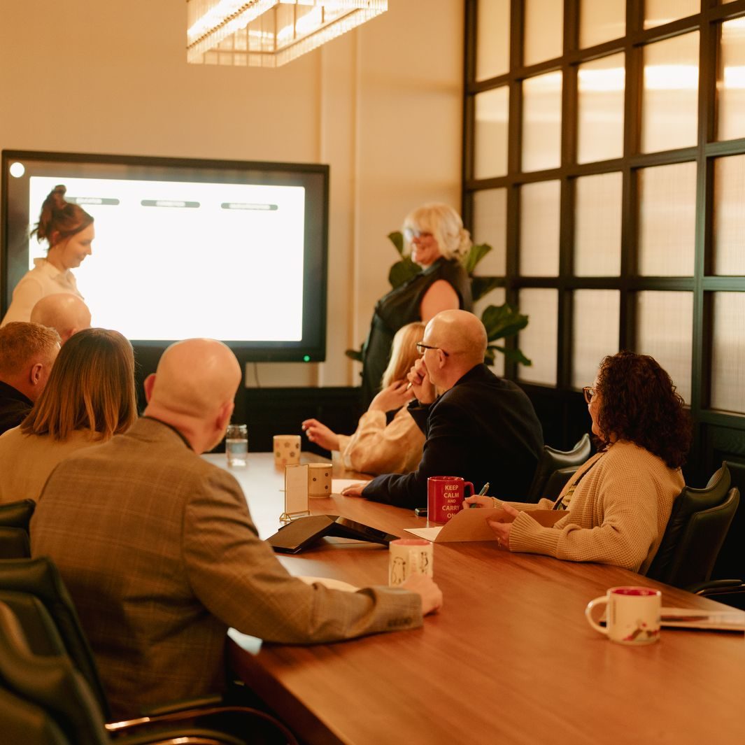 A group meeting around the long boardroom table beside the windows at Den 1880