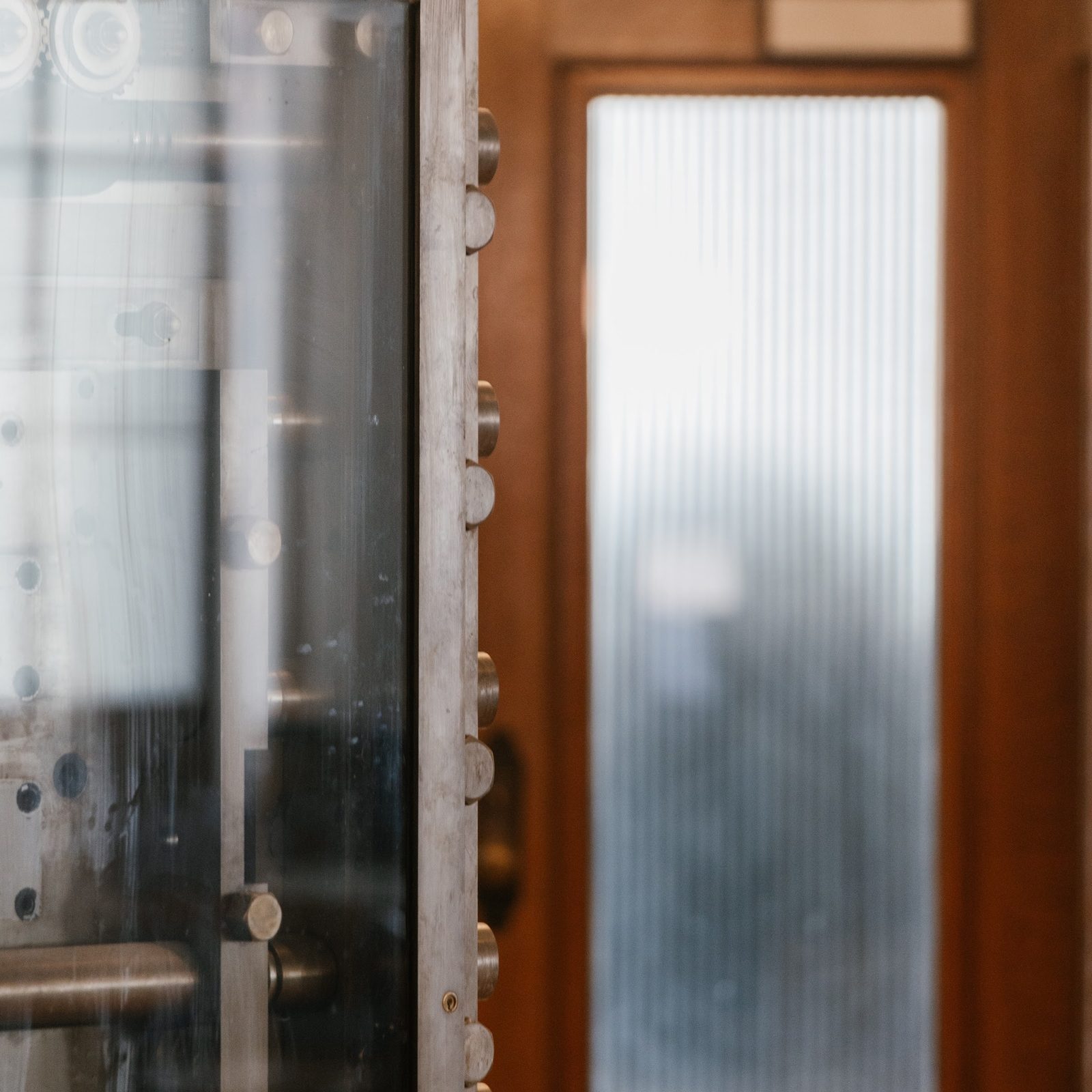 Close view of the original steel bank vault door, its bolts and 12-inch edge, beside the studio's inner door