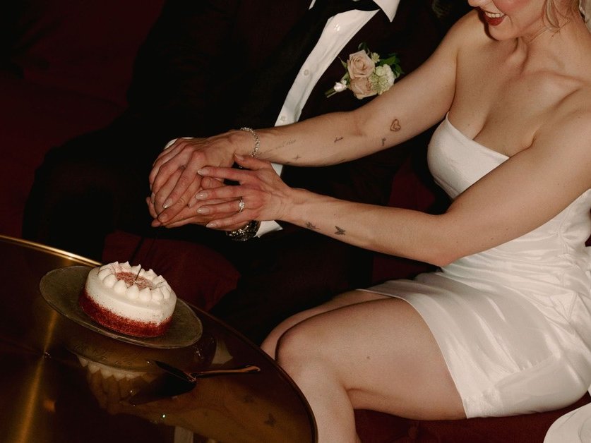 A bride and groom laughing while cutting the cake at Den 1880